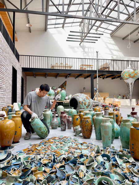 Artist Li Hongwei is in his Bejing studio smashing blue and orange crystalline glazed pots that he made.